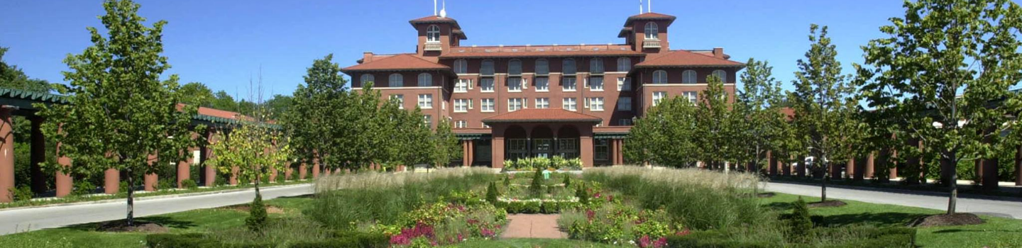 Large brick hotel with landscaped gardens and walkways.